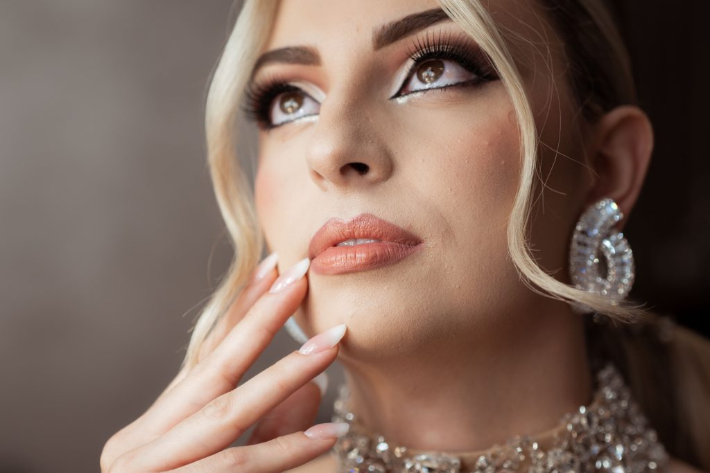 Close-up portrait of a woman with stylish makeup, sparkling earrings, and elegant hairstyle, expressing luxury.