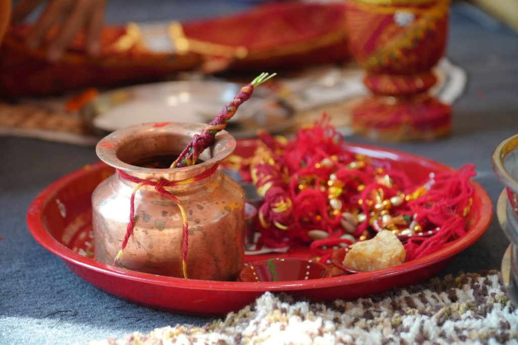 Close-up of a traditional Indian pooja thali with a copper pot and red decorations in Jaipur, India.